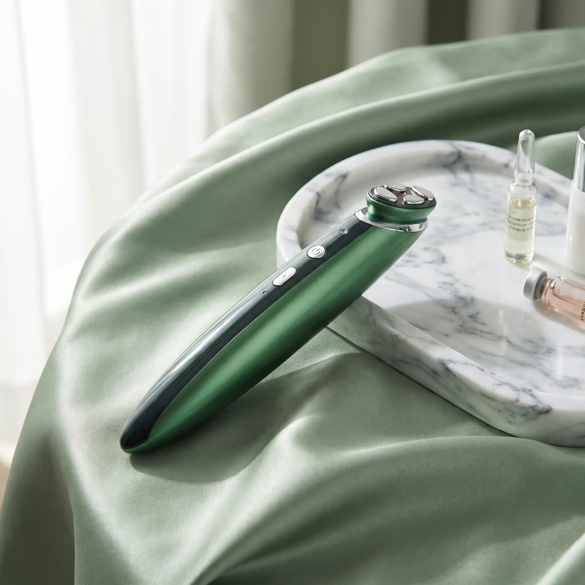 GlowEye Augenmassagegerät in Grün auf Marmorschale